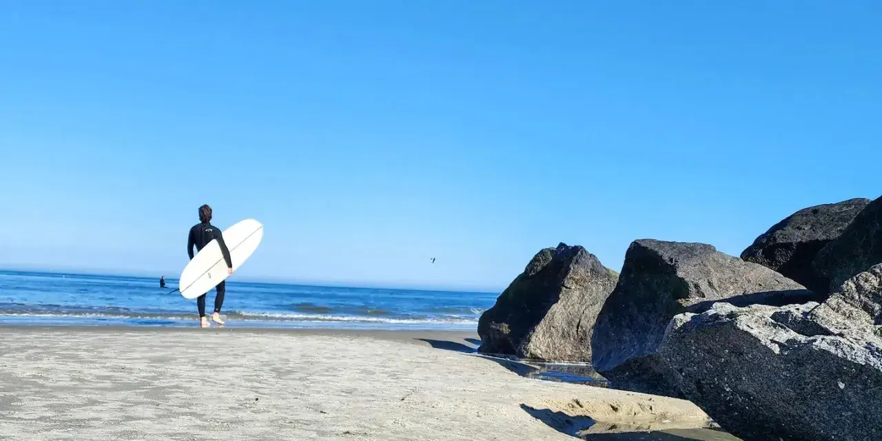 A surfer walking out to the ocean on Tybee Island, GA.