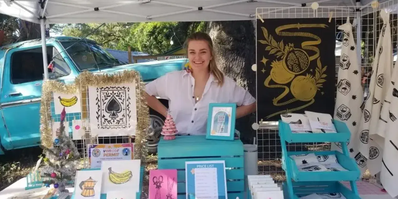 A woman at an outdoor vending tent with crafts.