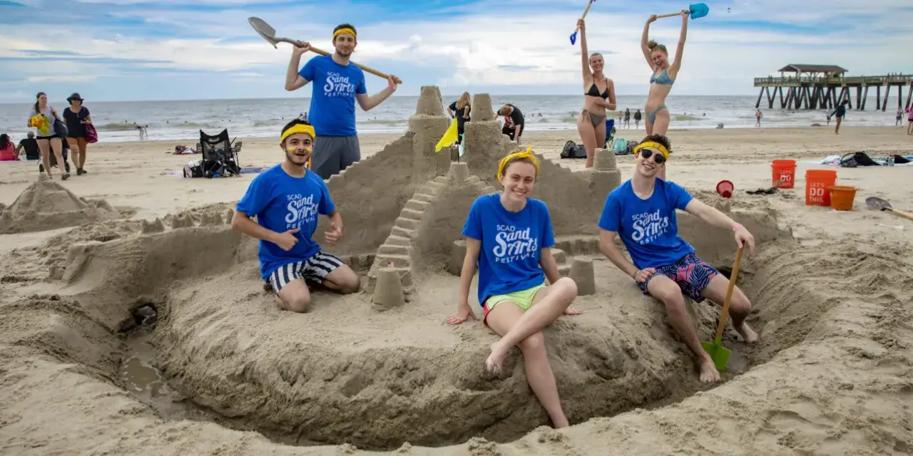 Group building sandcastle at SCAD Sand Arts Festival on Tybee Island beach in Georgia.