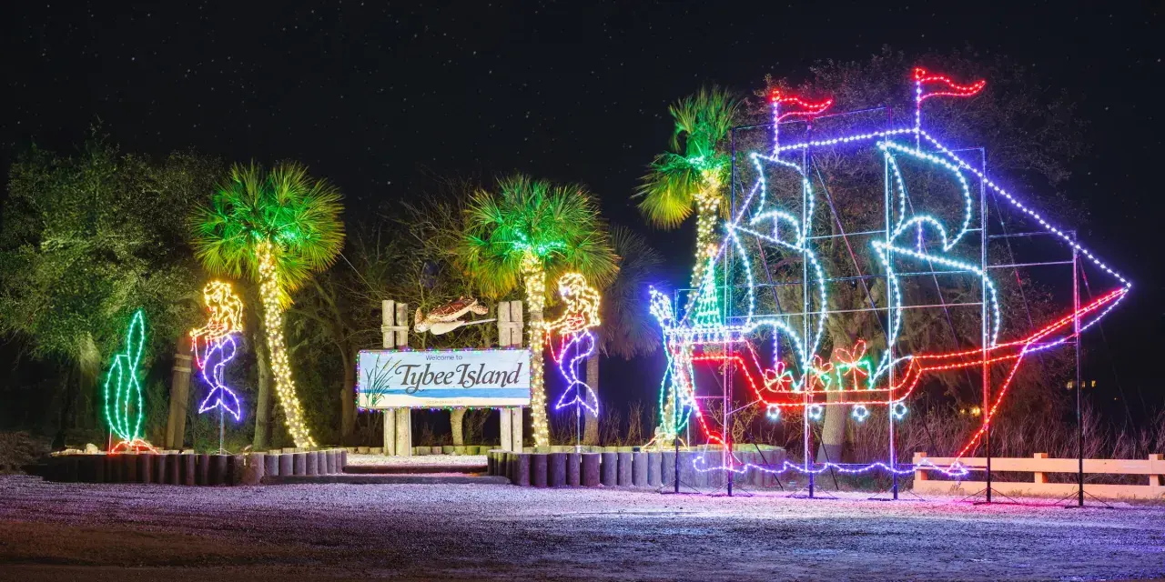 Palm trees and the Tybee Island sign decorated in holiday lights.