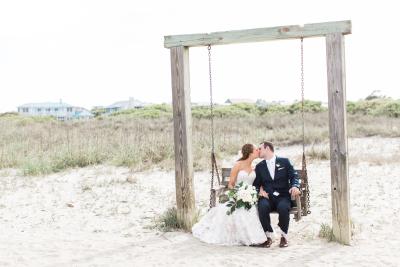 Bride and groom on beach swing.