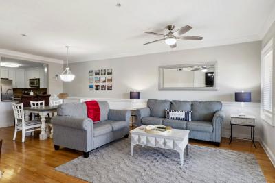A spacious living room area with ample seating and a view of the kitchen