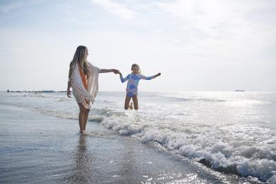 Mom and daughter on the beach playing in the ocean.