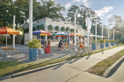 People eating outdoors at a restaurant with colorful rainbow umbrellas.