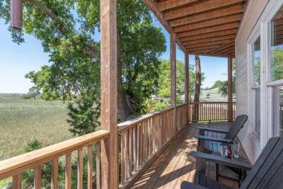 Sunset Hammock rental balcony overlooking Tybee Island’s serene marshes with Adirondack chairs.
