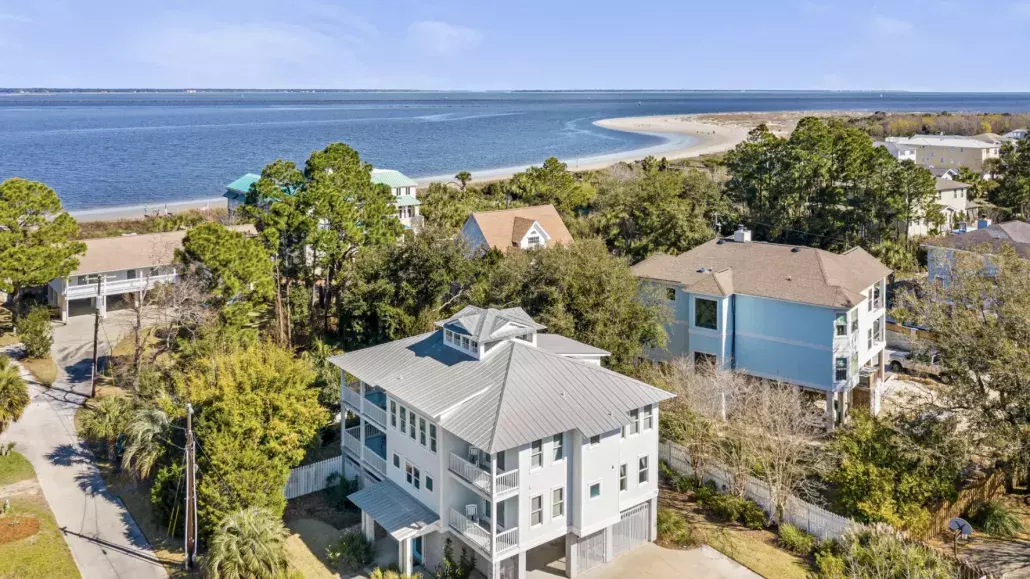Aerial view of Oceanfront Cottage Rentals’ Tybee Oasis rental home with a view of the ocean, beach and blue sky