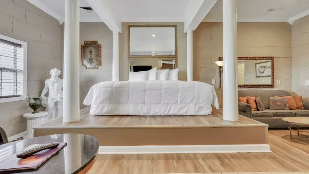 A Greek Mythology themed hotel suite with a large bed and white bedding.