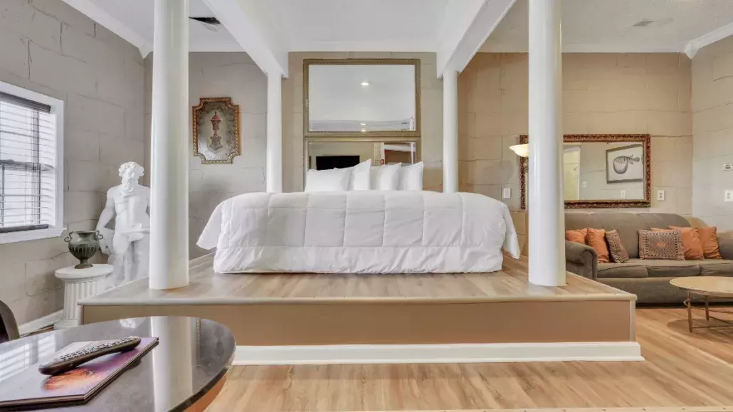 A Greek Mythology themed hotel suite with a large bed and white bedding.