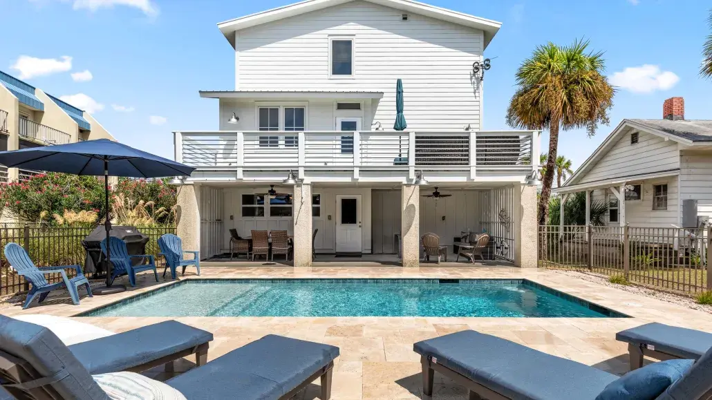 The backyard of a home’s outddoor pool house with seating.