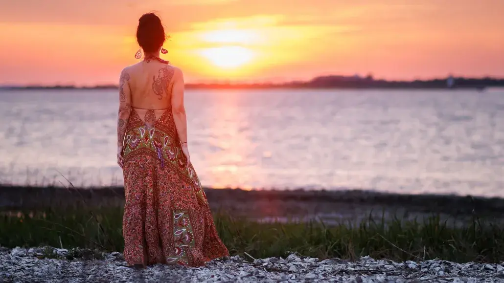 A woman standing on the beach watching the sunset.