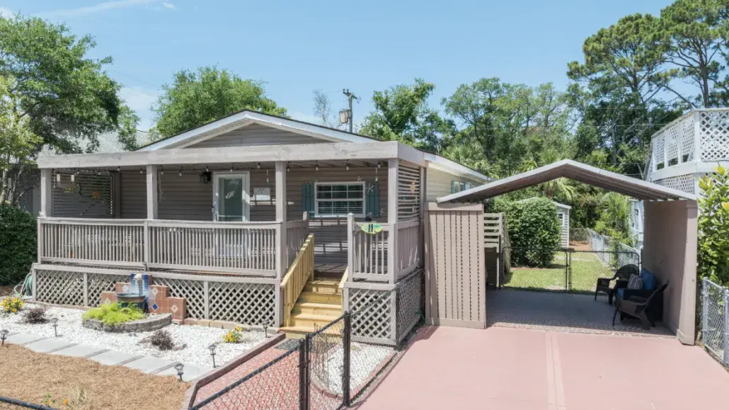 Exterior view of Good Tybations, a cozy pet-friendly Tybee Joy Vacation Rentals home with a covered porch, fenced yard, and shaded seating area.
