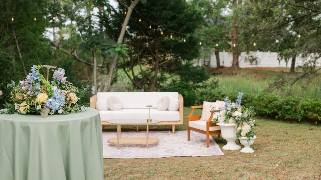 Outdoor wedding lounge with floral arrangements and string lights at The Chapel by the Sea.