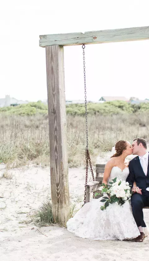 Bride and groom on beach swing.