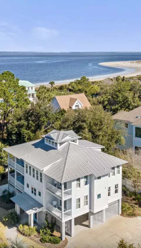 Aerial view of Oceanfront Cottage Rentals’ Tybee Oasis rental home with a view of the ocean, beach and blue sky