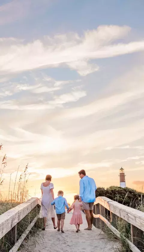 A family of four walking the dock towards the beach.