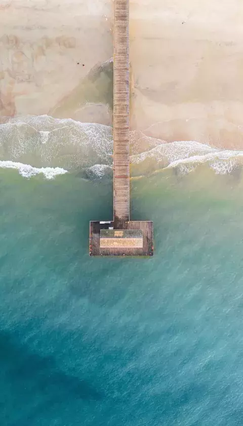 An aerial view of the top of a dock on the beach.