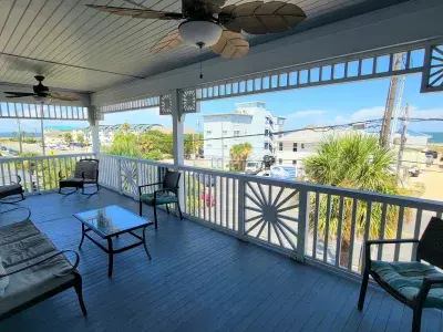Covered balcony with seating and partial ocean view