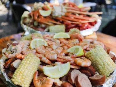 Plates of seafood including shrimp, corn, sausage and crab legs.