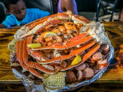 A shareable plate of crab legs, shrimp, corn on the cob and sausage.
