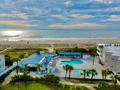 A resort aerial view with a pool and view of beach