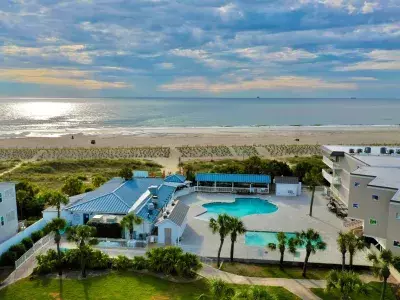 A resort aerial view with a pool and view of beach
