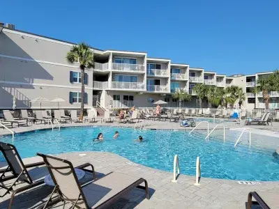 Resort condo and pool view with people swimming