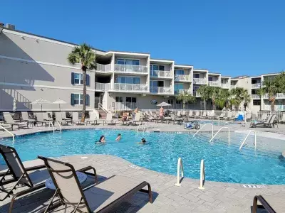 Resort condo and pool view with people swimming
