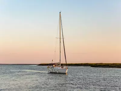 A sail boat on the ocean at sunset.