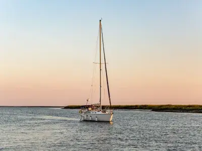 A sail boat on the ocean at sunset.