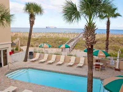 An outdoor pool view with seating, umbrellas and an oceanfront view