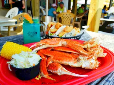 A seafood plate with crab legs, cole slaw and corn on the cob