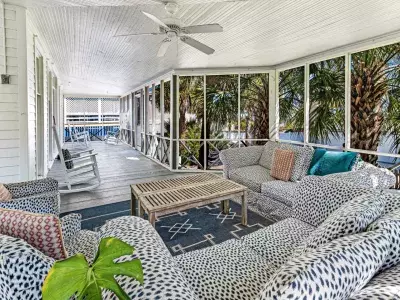 A large screened-in porch with couches and rocking chairs.