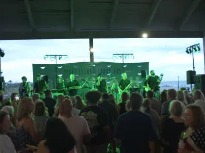 An outdoor concert with a huge crowd gathered around a stage of musicians
