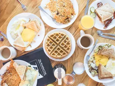 Plates of breakfast dishes on a table with cofee and orange juice