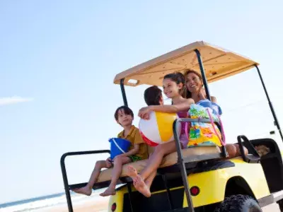 A family driving a golf cart on the beach
