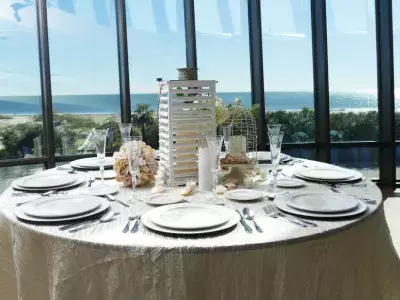 A dressed wedding table surrounded by windows overlooking the ocean.
