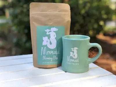 A coffee bag and coffee cup sitting on a table with a white tablecloth.