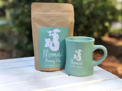 A coffee bag and coffee cup sitting on a table with a white tablecloth.