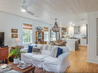 Spacious living room with white walls and beach cottage aesthetics with a view of the kitchen