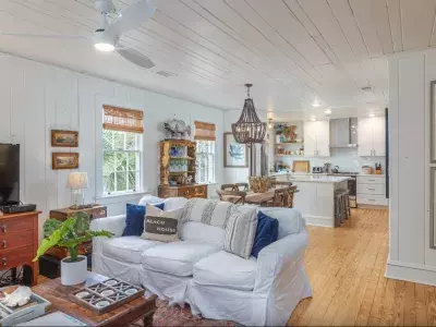 Spacious living room with white walls and beach cottage aesthetics with a view of the kitchen