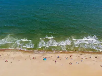 An aerial view of the beach with waves washing along the sand.