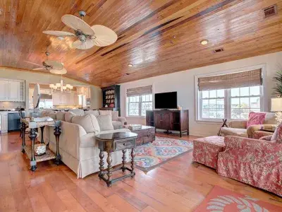 A spacious vacation home living room with seating and a view of the kitchen.