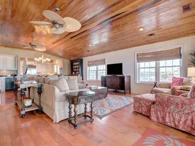 A spacious vacation home living room with seating and a view of the kitchen.