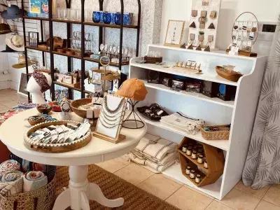 A retail store with shelves and a table of accessories such as jewelry, hats, headbands and scarves.