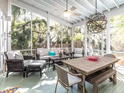 A covered outdoor screened in deck with ample seating.