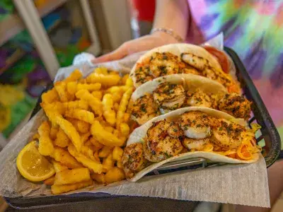 A plate of grilled shrimp tacos and fries.