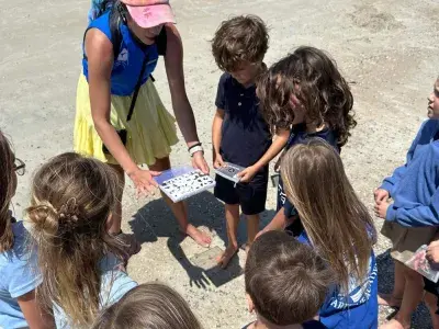 A group of children collecting fossils on the beach with a guide.