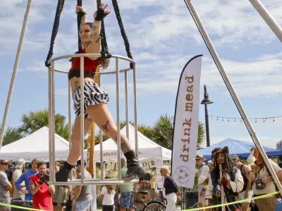 A woman performing aerial acts outdoors at a carnival.