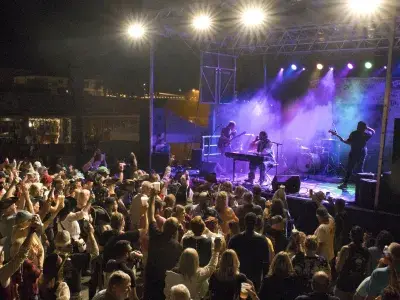 A large crowd of people listening to musicians on stage at night.
