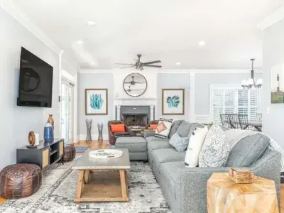 Spacious coastal living room at A Wave From It All featuring a large sectional sofa, neutral tones, modern decor and an open layout.